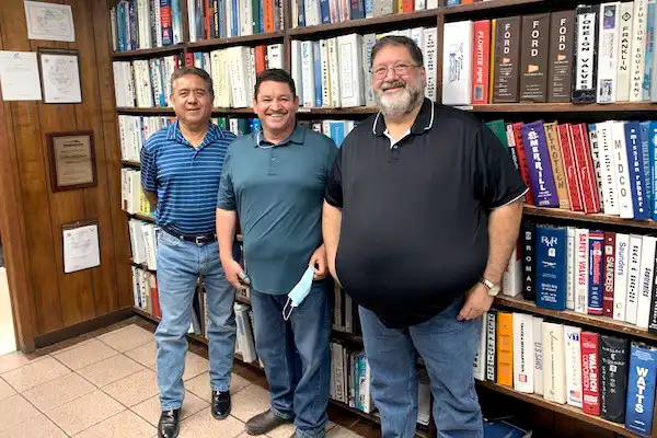 Trois collègues chez Clowe & Cowan of El Paso posant devant une bibliothèque remplie de livres